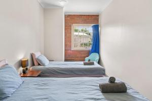 Dos camas en una habitación con ventana. en Modern retreat- private entrance - free parking, en Kingston