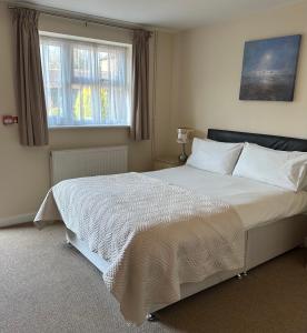 a bedroom with a large white bed with two windows at Newent Golf Club and Lodges in Newent