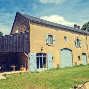 un grand bâtiment en briques avec des portes bleues sur un champ dans l'établissement L'Armance - Magnifique Maison typique morvan avec piscine, à Nuars