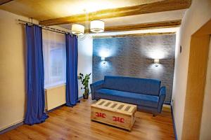 a living room with a blue couch and a table at Apartamenty Folwark Malinowy Chruśniak in Bisztynek