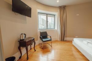 a bedroom with a bed and a chair and a desk at Boutique Suites by Hosty in Porto