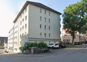 a white building with cars parked in front of it at Löwe Apartment Blau Neuhausen am Rheinfall in Neuhausen am Rheinfall