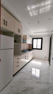 an empty kitchen with white cabinets and a window at Résidence Yasmine in Ksour Essaf