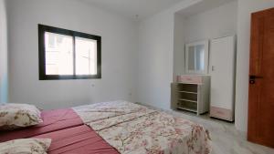 a white bedroom with a bed and a window at Résidence Yasmine in Ksour Essaf