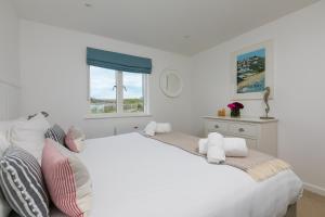 a white bedroom with a large white bed and a window at 64 Una in Carbis Bay +24 photos