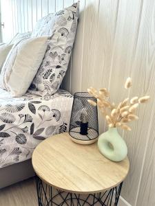 a table with a vase on it next to a bed at Le Cocon, 100m de la plage, place de parking privé in Saint-Hilaire-de-Riez