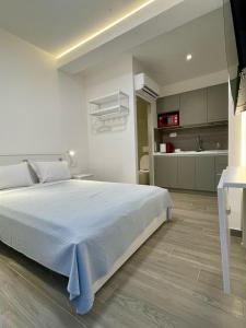 a bedroom with a large white bed and a kitchen at Agora LX Studios & Suites in Thessaloniki
