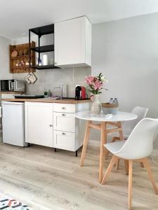 a kitchen with white cabinets and a table and chairs at Studio Polvo in Parede
