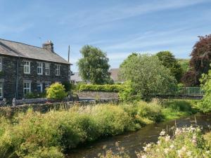 ein Haus neben einem Fluss mit einer Brücke in der Unterkunft Riverside Cottage with secure bike storage in Staveley