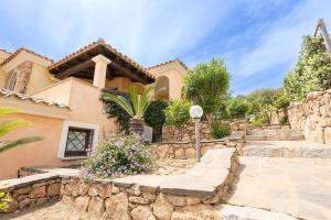 a villa with a stone wall and a house at Perla Marina in Porto San Paolo