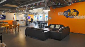 a living room with couches and a table and a restaurant at CheapSleep Hostel Helsinki in Helsinki