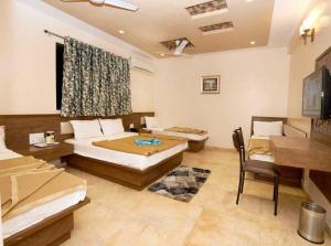 a bedroom with two beds and a table and a desk at Hotel Sai Suraj Park in Shirdi