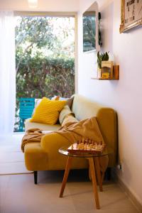 a living room with a yellow couch with chessetts on a table at La RESIDENCE in Roquebrune-Cap-Martin +18 photos