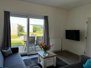 ユリアーナドルプにあるBungalow Noordzee Dのソファとテレビのあるリビングルーム