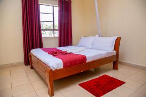 a bedroom with a bed with red curtains and a window at Museum View Hotel Kisumu in Kisumu +22 photos