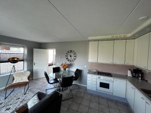 ユリアーナドルプにあるBungalow Noordzee Aのテーブルと壁に時計があるキッチン