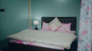 a bedroom with a bed with pink pillows at Swagatam Homestay in Darjeeling