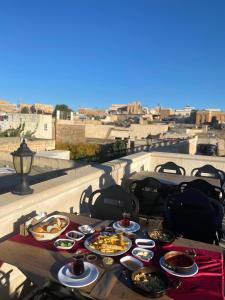 a table with plates of food on a balcony with a view at Midyat Amaara Konağı Otel&Cafe in Midyat