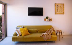 a living room with a green couch and a tv at La RESIDENCE in Roquebrune-Cap-Martin