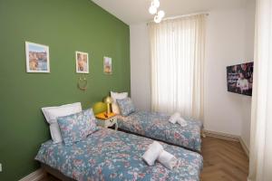 two beds in a small room with green walls at LE LYNX HAUSSMANIEN appartement tout confort, climatisé avec parking privé, à deux pas du centre in Colmar