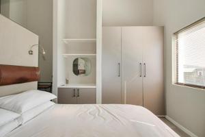 Un dormitorio blanco con una cama y una ventana. en The Paddocks Dainfern, en Fourways