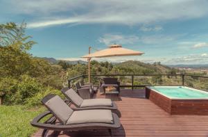 a deck with chairs and a swimming pool and an umbrella at Vista Bonita - Hacienda Guatape in Guatapé