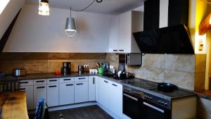 a kitchen with white cabinets and black appliances at Gasthof Wedding in Bielefeld +28 photos