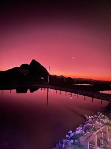un tramonto su un corpo d'acqua con una montagna di Cabana Harmony | Jacuzzi I Vista pro Lago a Alfredo Wagner Altre 31 foto