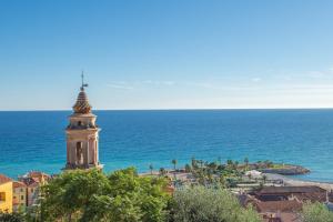 a building with a cross on top of it next to the ocean at MAISON VIEUX CHÂTEAU - Vue Mer imprenable - Menton Vieille Ville in Menton