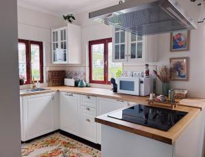 a kitchen with white cabinets and a sink and a microwave at Casa da Madrinha in Tuias