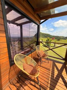 two chairs on a deck with a view of the mountains at Cabana Jardim Encantado in Barracão