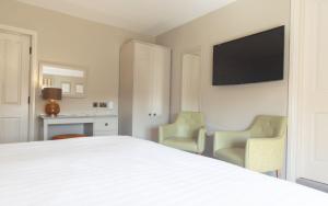 a bedroom with a white bed and two chairs at Heacham Manor Hotel in Hunstanton
