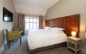a bedroom with a large bed and a desk and a television at Heacham Manor Hotel in Hunstanton