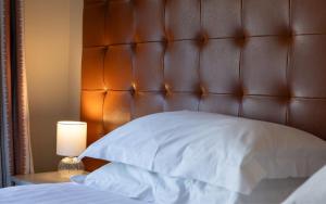 a bed with a brown leather headboard and a lamp at Heacham Manor Hotel in Hunstanton