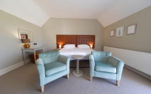 a bedroom with a bed with two chairs and a table at Heacham Manor Hotel in Hunstanton