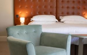 a bedroom with a bed and a chair and a table at Heacham Manor Hotel in Hunstanton