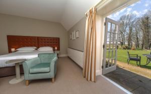 a bedroom with a bed and a chair and a window at Heacham Manor Hotel in Hunstanton