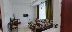 a living room with a couch and chairs and a window at Rose Villa in Malabe