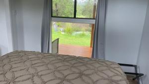 a bedroom with a bed and a large window at Private country 1 Bedroom Cabin in Landsborough