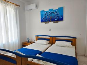two twin beds in a bedroom with blue and white at Villa Dolphin in Azolimnos Syros +23 photos