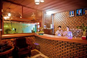 two people standing at a bar with a fish tank at RaVorn Villa Boutique in Battambang +79 photos