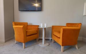 two orange chairs and a table with a tv at Heacham Manor Hotel in Hunstanton