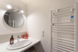 une salle de bain blanche avec un lavabo et un miroir dans l'établissement Les Sablons - Magnifique Vue Port, à Saint-Malo