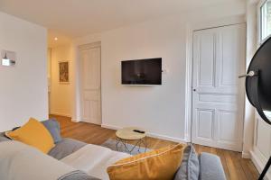ein Wohnzimmer mit einem Sofa und einem Fernseher an der Wand in der Unterkunft Le Cocon des halles * Ideal Couple ou solo * WiFi * Élégance * Pieds des Halles in Troyes