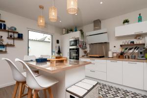 a kitchen with white cabinets and a counter with stools at Ty Laouen in Quiberon +17 photos