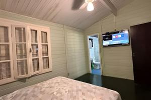 a bedroom with a bed and a flat screen tv at Linda Casa em Juquehy - SP (3) in São Sebastião