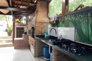 eine Küche mit einer Arbeitsfläche, die mit einem Spülbecken und einem Herd ausgestattet ist in der Unterkunft Linda Casa Piscina no Sertão de Cambury - SP (2) in Camburi