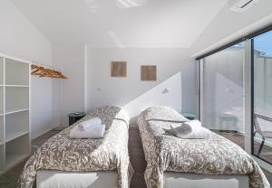 Dieses weiße Zimmer verfügt über 2 Betten und einen Balkon. in der Unterkunft Casinha da Rita by Home Sweet Home Aveiro in Aveiro