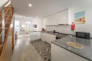 eine Küche mit weißen Schränken und einer Arbeitsplatte in der Unterkunft Casinha da Rita by Home Sweet Home Aveiro in Aveiro