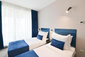 two beds in a hotel room with blue accents at Art Plaza Hotel in Sofia